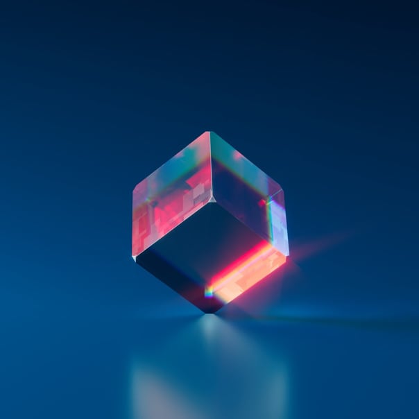 Clear blue cube with red light reflected on the edges, balancing on a corner.